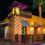 The exterior facade of the Flying Iguana in Neptune Beach at night. An iconic corner has been created by covering about 11 feet of each adjoining wall from knee-height to rooftop with the 10" Tradewinds pattern decorative cement tile.