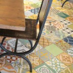 A close-up of the Flying Iguana dining room, focused on a table and chairs, with a good view of the floor. The floor is covered with a select mix of patchwork cement tile from Villa Lagoon Tile.