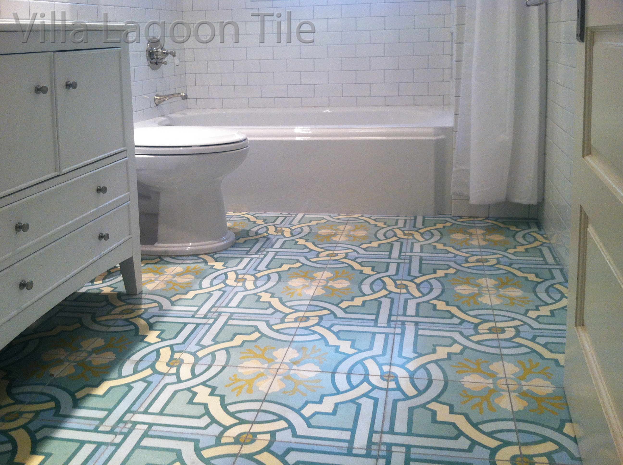 Villa Lagoon Tile's original "Venetian Azul" cement tile brings a white bathroom to life.