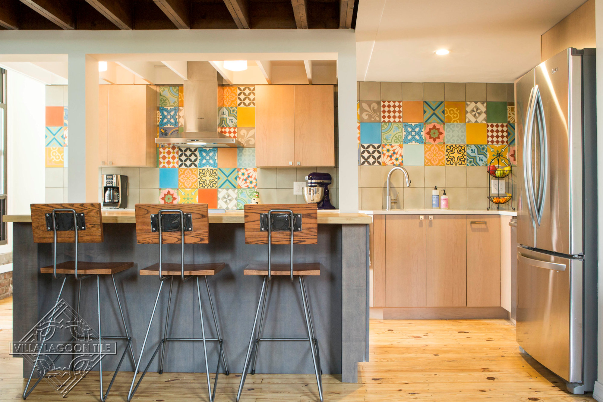 Small kitchen with colorful patchwork and solid cement tiles covering the wall.