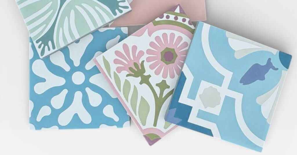 An assortment of colorful decorative cement tiles featuring floral and geometric patterns in soft pastel blue, pink, and green.