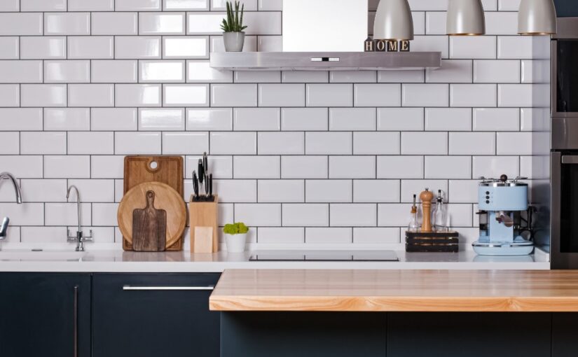 A kitchen with white tile as a backsplash. There is an island with a wood countertop and cabinets painted blue.