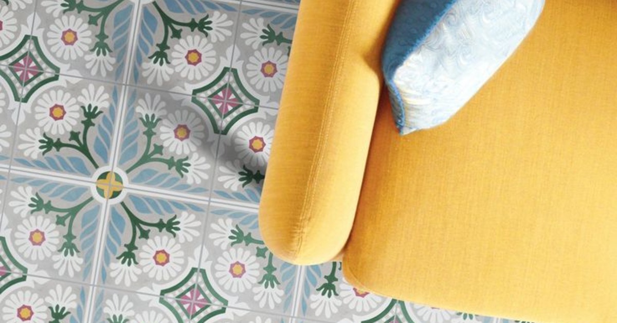 A yellow chair is placed on a floor that has a blue tile pattern. There are green accents on the tile as well.