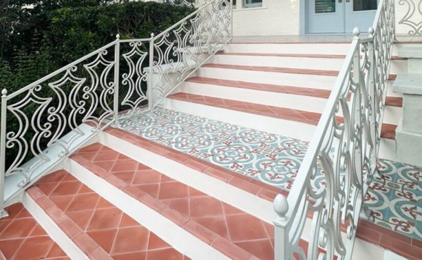A staircase is leading up to a door. There is a landing about halfway up the staircase with tiles.