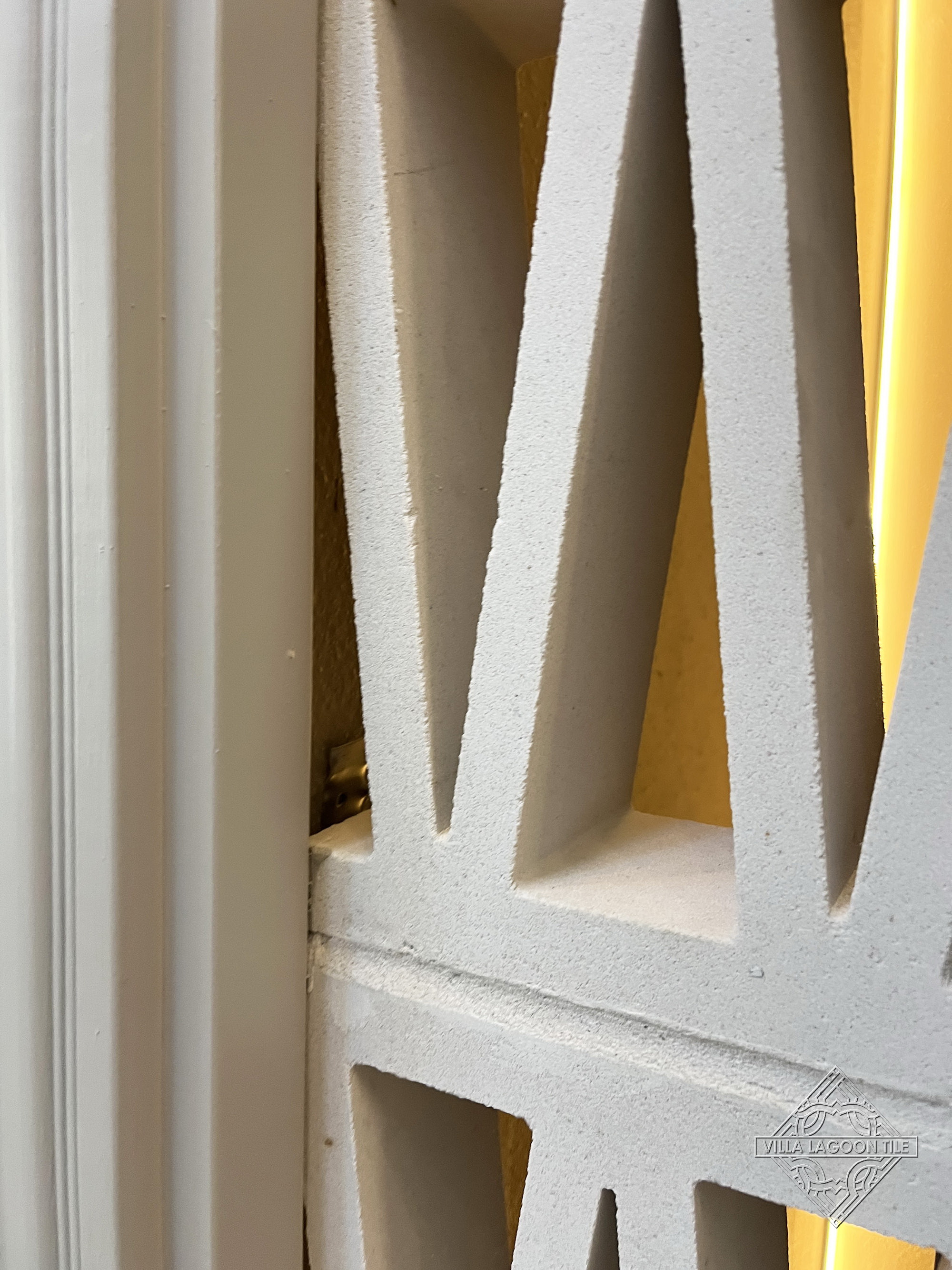 Close-Up Detail of White Geometric Cement Breeze Block with Backlit Texture and Joinery