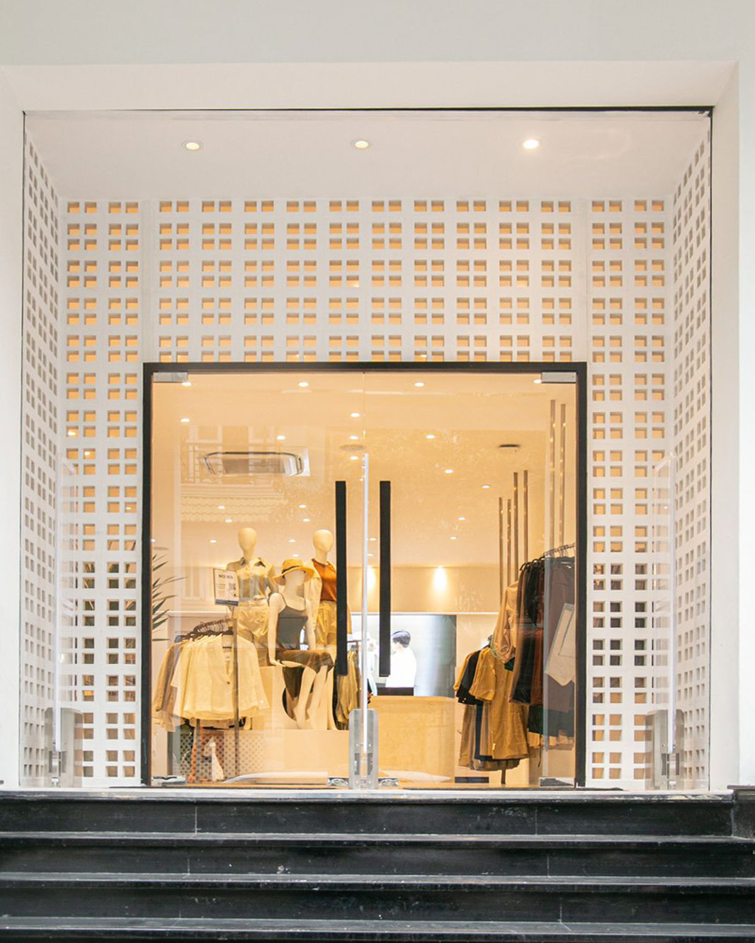 Modern Boutique Entryway: Glass Storefront Framed by White Geometric Breeze Blocks